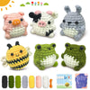 A set of seven crochet animals including a pig, a cow, a rabbit, a bee, and two frogs, along with yarn and needles.
