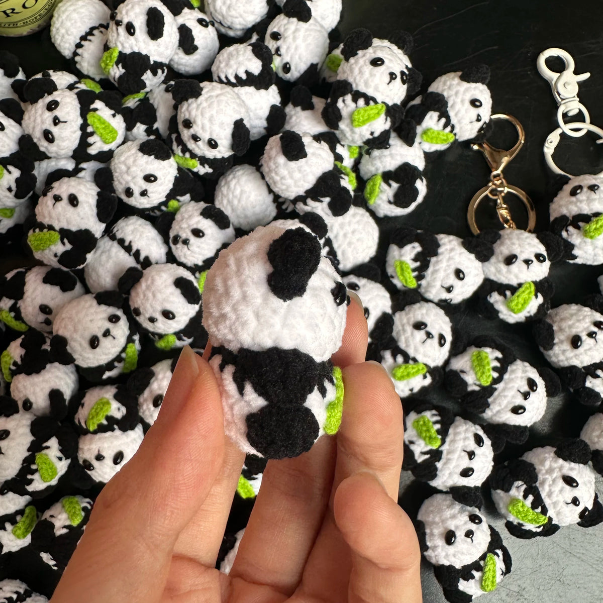 A hand holds a white and black crochet kitten charm used as a keyring.