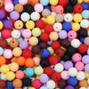A close-up view of a large pile of colorful matte acrylic beads in various shades including pink, yellow, orange, purple, and