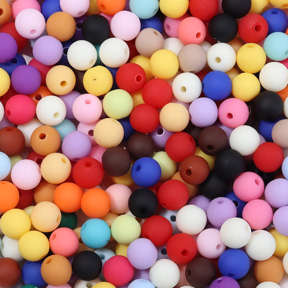 A close-up view of a large pile of colorful matte acrylic beads in various shades including pink, yellow, orange, purple, and