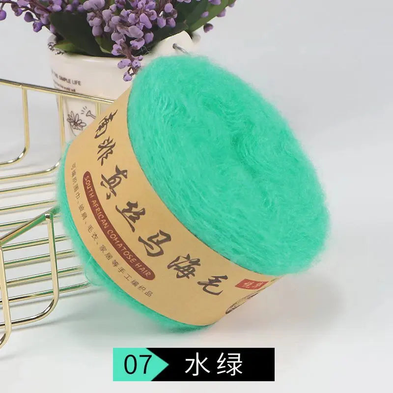 A ball of bright turquoise silk mohair blended yarn is displayed next to a gold wire rack.