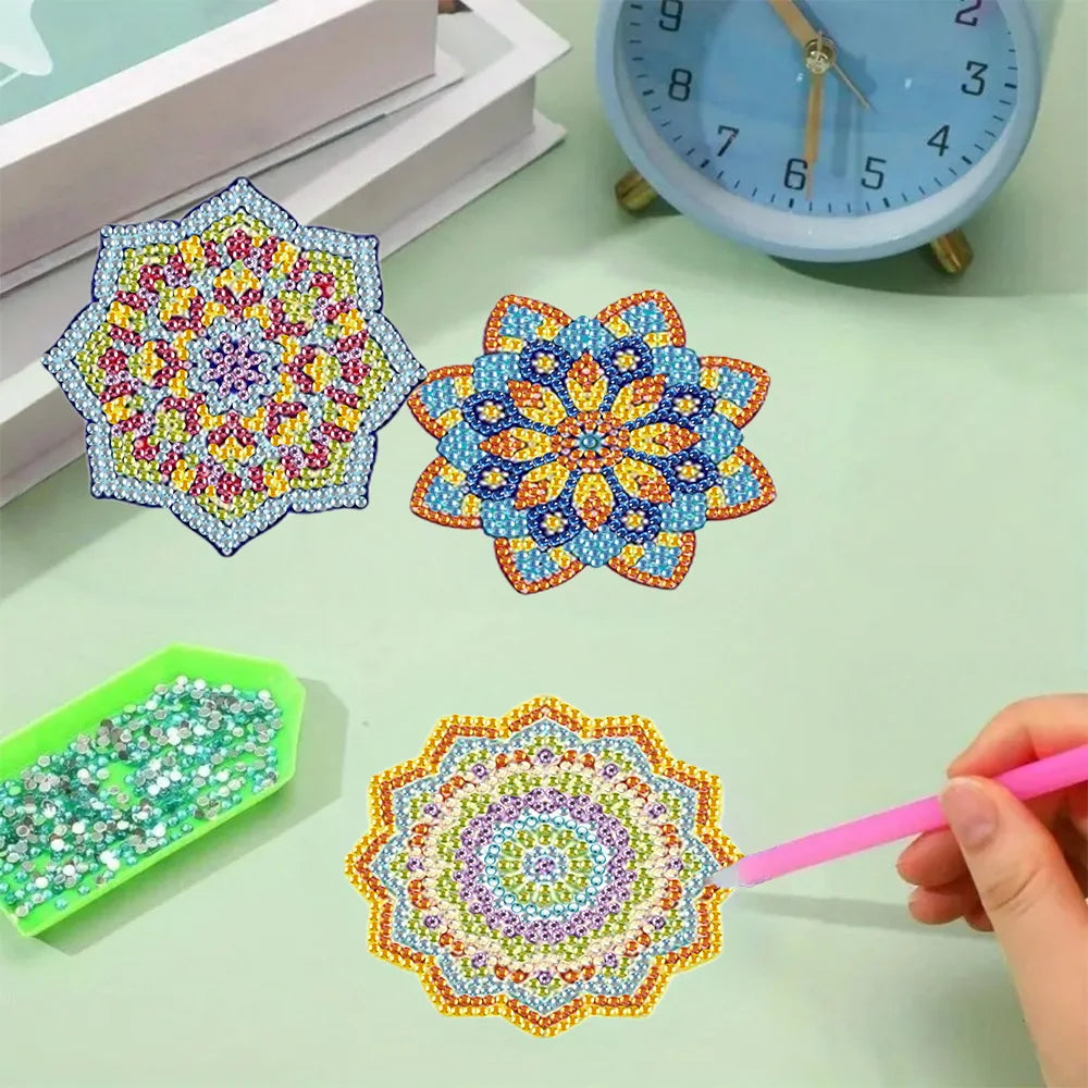 A hand is painting a colorful diamond painting flower design on a green surface, next to a blue clock and a green holder.