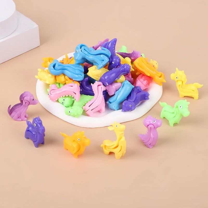 A pile of colorful, squishy animal and dinosaur sensory stress bracelets for kids scattered on a light background.
