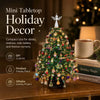 A miniature, fully decorated holiday Christmas tree made of colorful beads and crystals, displayed on a wooden surface.