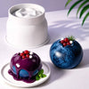 A vibrant blue fruit with red and white berries sits next to a white silicone mold and a plate.