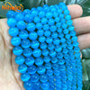A hand holds a strand of bright blue cat eye stone beads for jewelry making