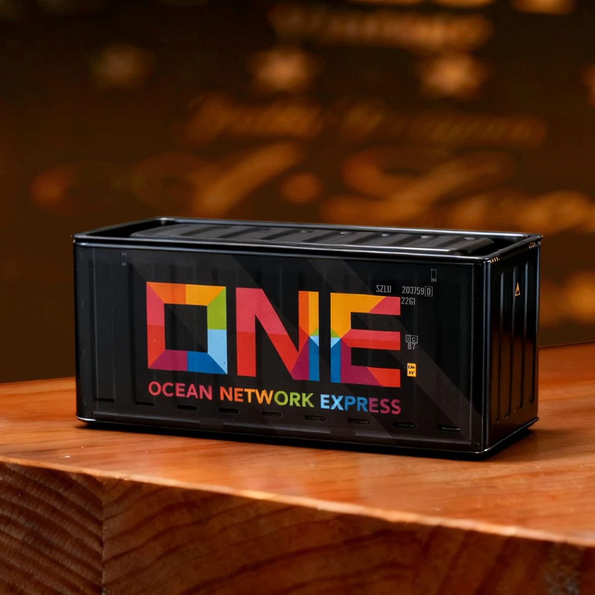 A black industrial iron storage box labeled ONE OCEAN NETWORK EXPRESS resting on a wooden surface.