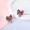 A sterling silver butterfly charm with red enamel and clear stones is displayed on a white background.