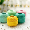 A ball of bright yellow crochet thread resting on a white surface with blurred background elements.