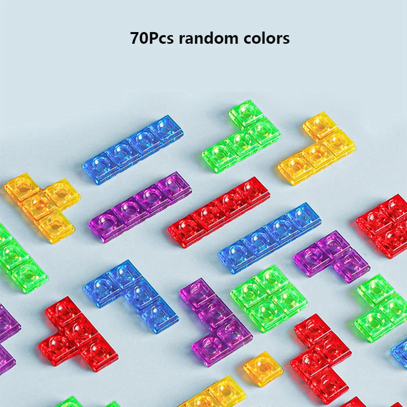 A collection of 70 pieces of random colored 3D puzzle building blocks scattered on a light gray surface.