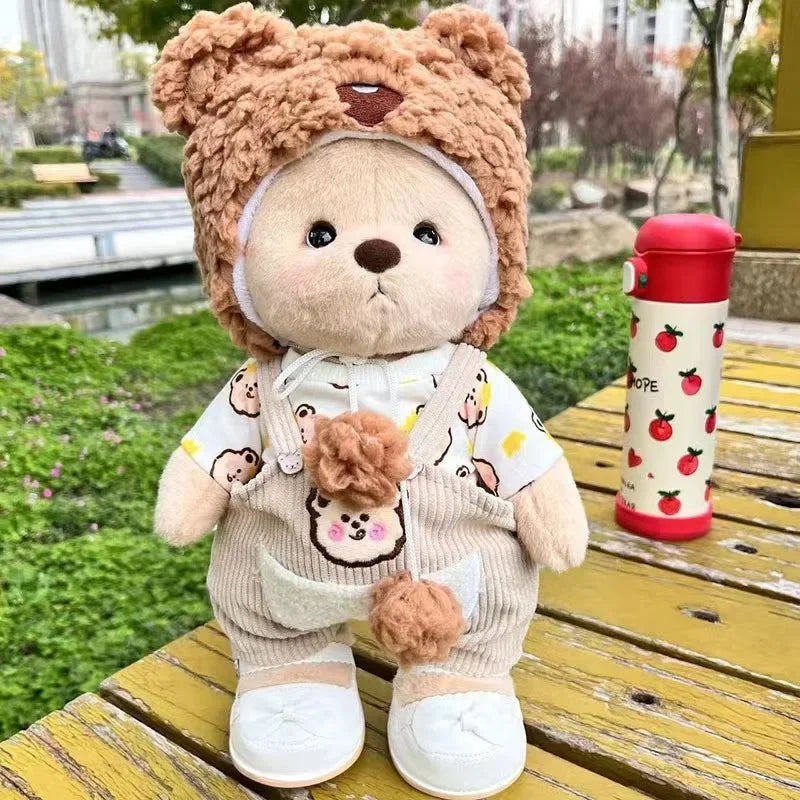 A brown teddy bear plush wearing a white dress and holding a small pom-pom.