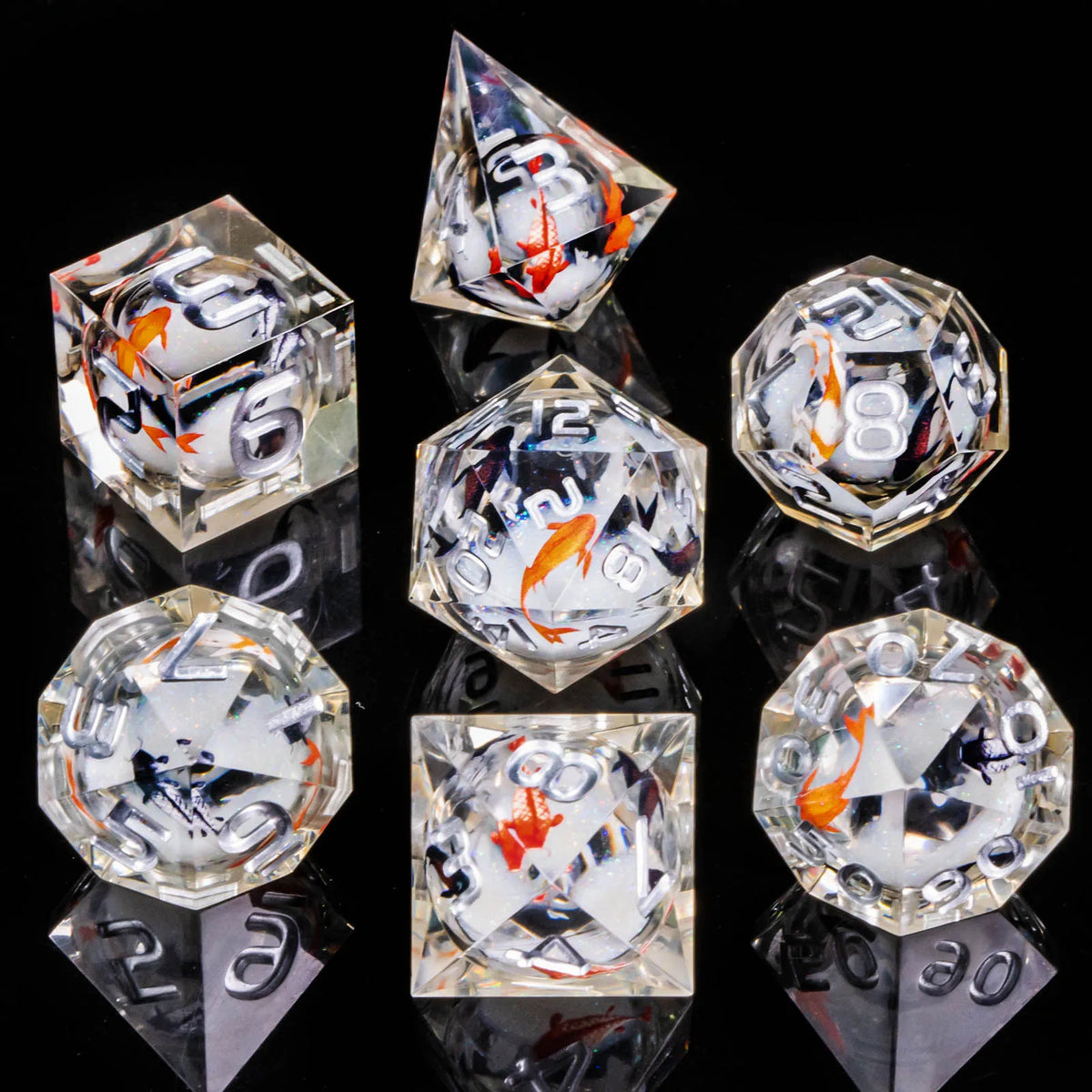 A collection of clear resin dice set with sharp edges, featuring white and orange markings, displayed on a reflective surface