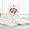 A baby wearing a white hooded animal bath towel, likely a bear design, is shown indoors.