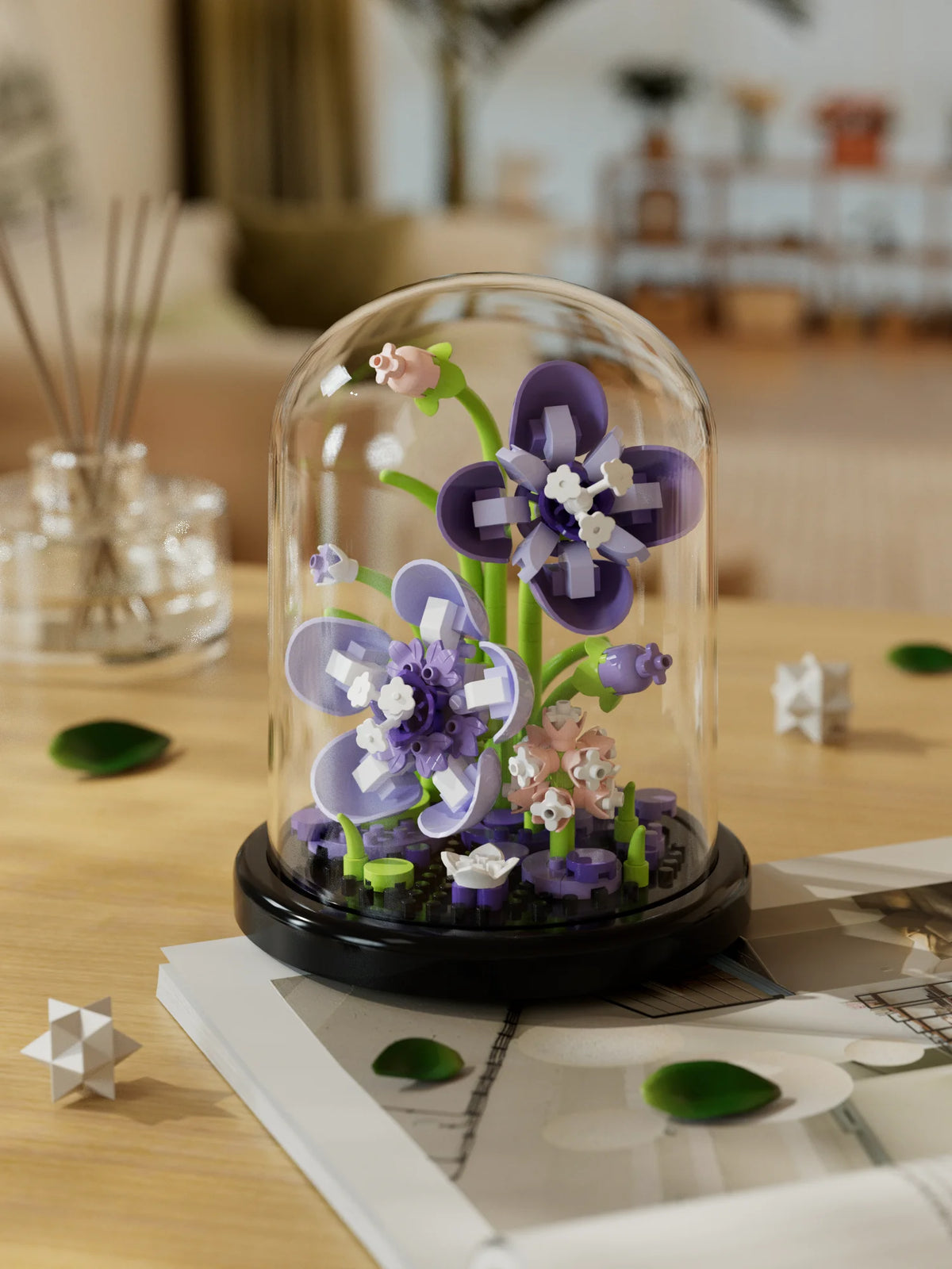 A glass dome terrarium containing purple and pink flowers and moss, resting on a wooden table.