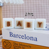 White cube shaped baby cake toppers with the word BABY and a measurement scale on a book.