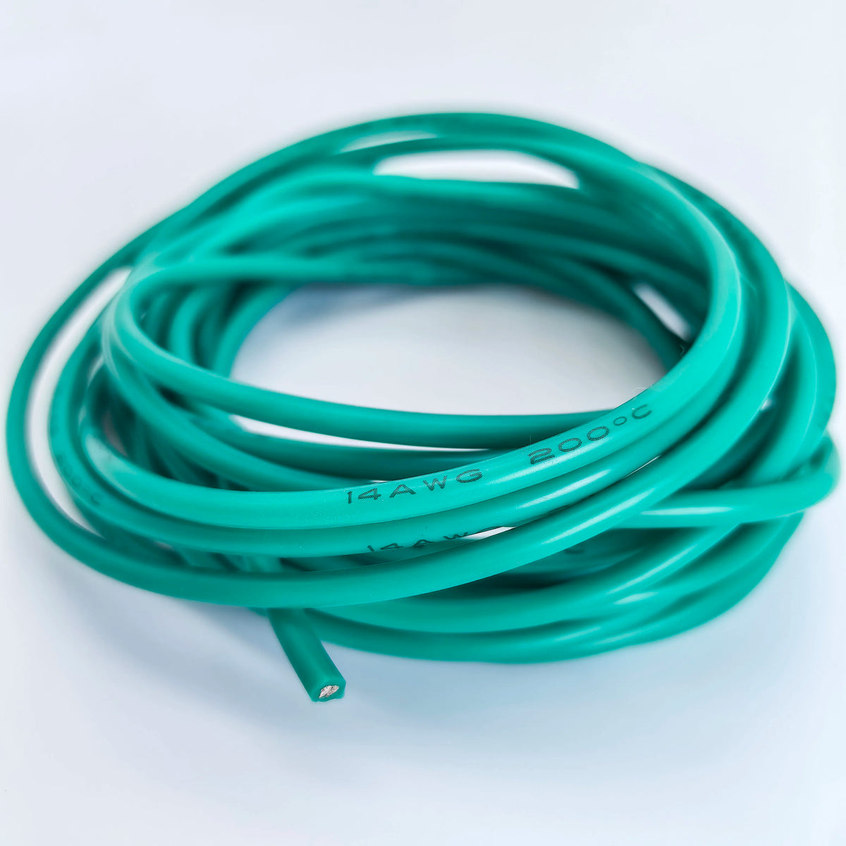 A coil of green flexible silicone tinned copper wire with multiple AWG gauges coiled on a white surface.