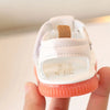 Une paire de sandales d'été roses antidérapantes pour bébés avec un motif ours et une lanière texturée tenue dans une main.