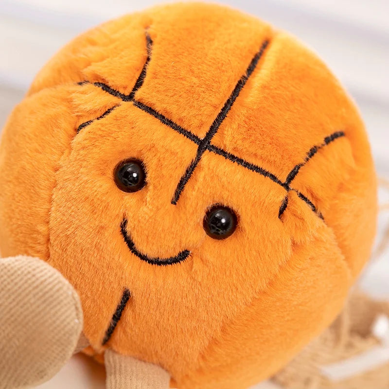 An orange plush sports ball companion with stitched lines and small black eyes is being held by a hand.