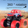 A red and blue four-wheel drive stunt car with large red tires is shown in a desert landscape.