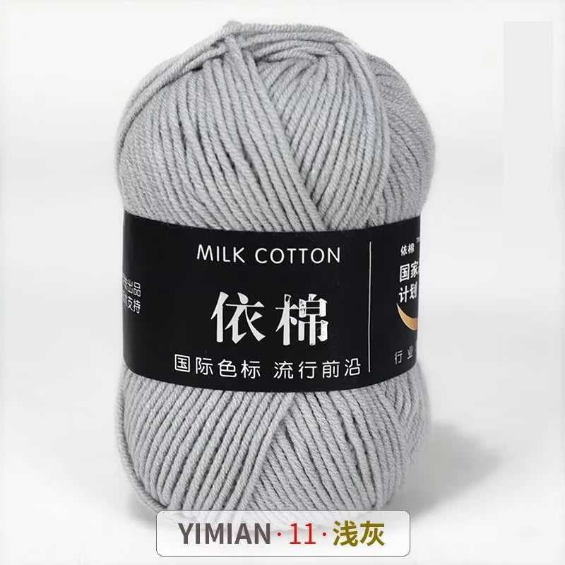 A ball of gray milk cotton yarn with a black label indicating YIMIAN 11 and washing instructions.