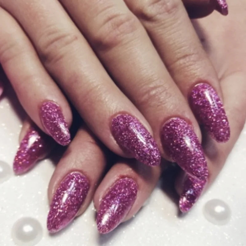Close-up of hands displaying long nails coated with vibrant purple holographic glitter polish.