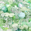 A close-up of mixed clear and light green acrylic loose beads for jewelry making.