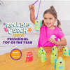 A young girl is playing the Reel Big Catch game with green and yellow fishing rods and lures on a wooden table.