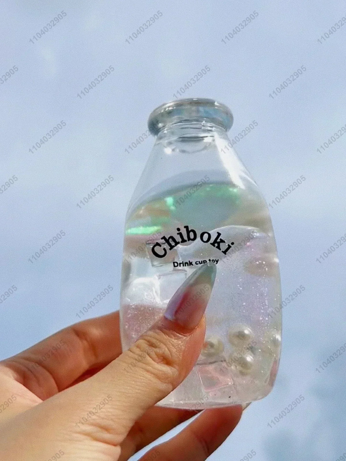 A hand holds a clear plastic bottle filled with liquid and small bubbles, labeled Chiboki, which is a fruit bottle stress bal