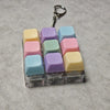 A set of pastel colored keyboard keychains or fidget toys with metal clasps arranged in a row.