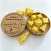 A set of yellow polygonal cheese dice inside a cardboard container with a label for Loch's Fromagerie