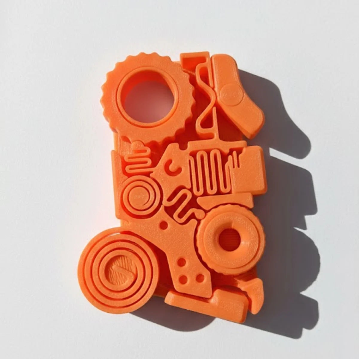 Orange 3D printed fidget toy featuring gears, springs, and rollers for stress relief