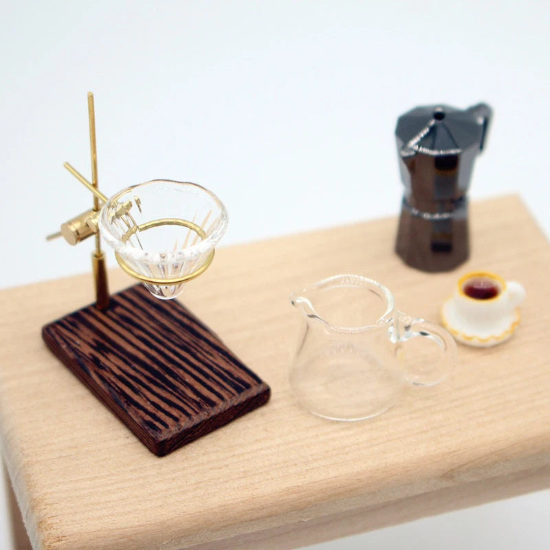 A miniature hand-brewed coffee stand set for dollhouse featuring a brass coffee filter and a small glass cup.