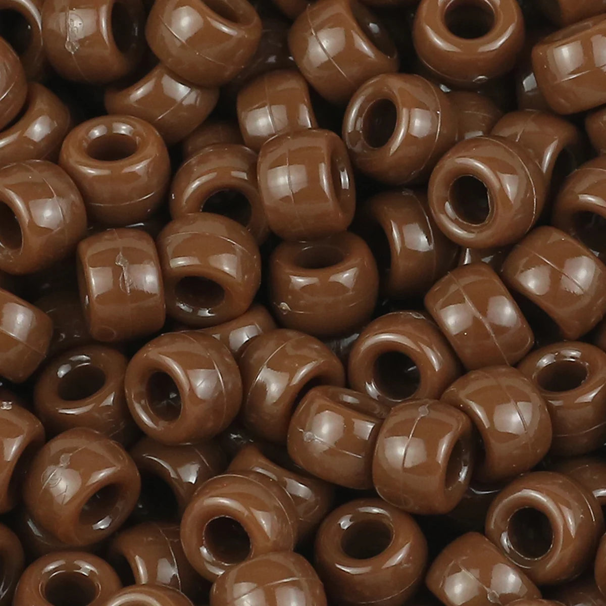 A close-up view of small, solid brown pony beads used for jewelry making and craft projects.