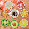 Sous-verres de peinture diamant avec des tranches de fruits comme l'agrumes et le kiwi sur une surface en bois.
