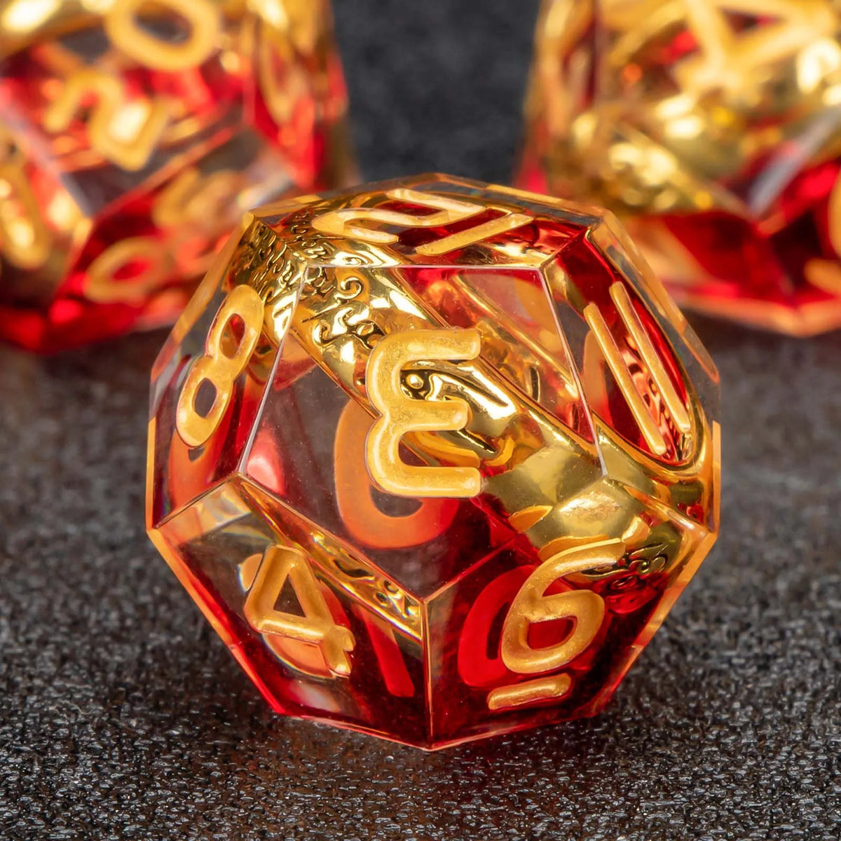 A close-up of a translucent red resin die with golden elven numbers, resting on a dark surface.