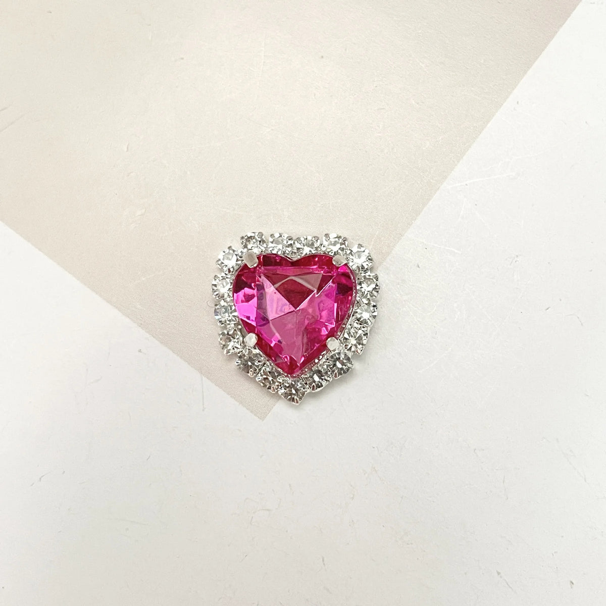 A heart-shaped gemstone pendant surrounded by clear rhinestones for DIY crafts.