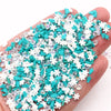 A hand holds a pile of iridescent polymer clay slices in shades of teal and white for DIY crafts.