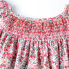 A pink and white floral smocked summer dress with ruffled neckline and flying sleeves.