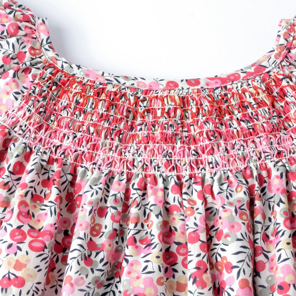A pink and white floral smocked summer dress with ruffled neckline and flying sleeves.