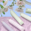 A collection of pink and green adhesive dot tape glue rollers displayed on purple and pink textured paper.