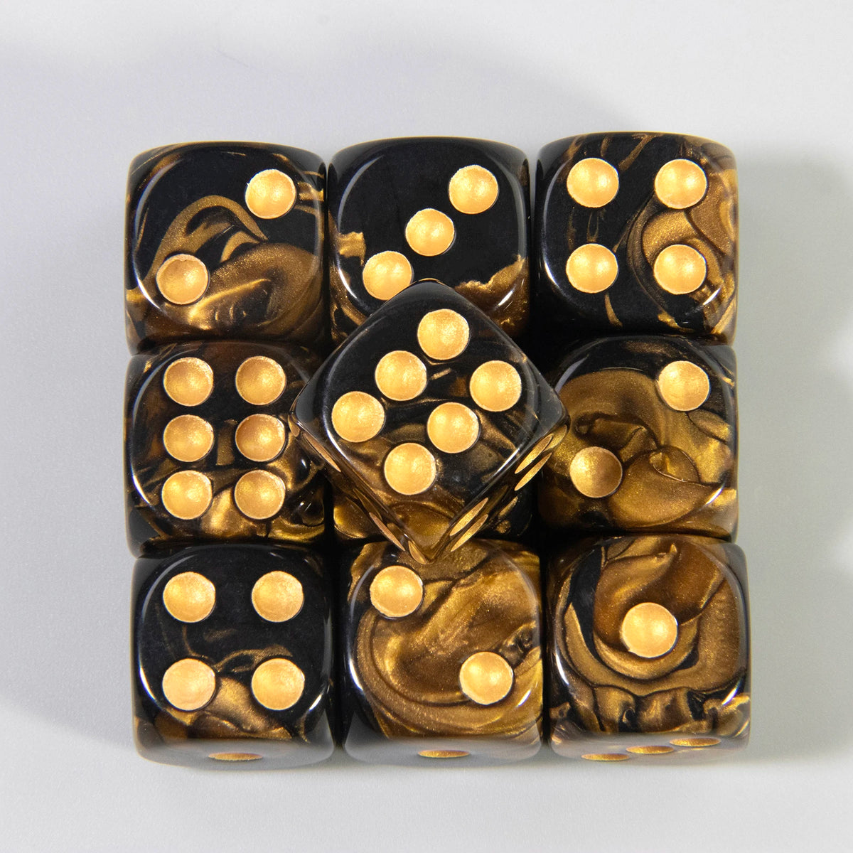 A set of ten 16mm acrylic poker dice with gold and black marbled coloring arranged in a stack.