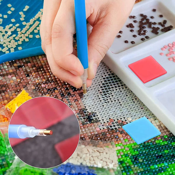 A hand is using a tool to place a red piece of diamond painting onto a mosaic background.