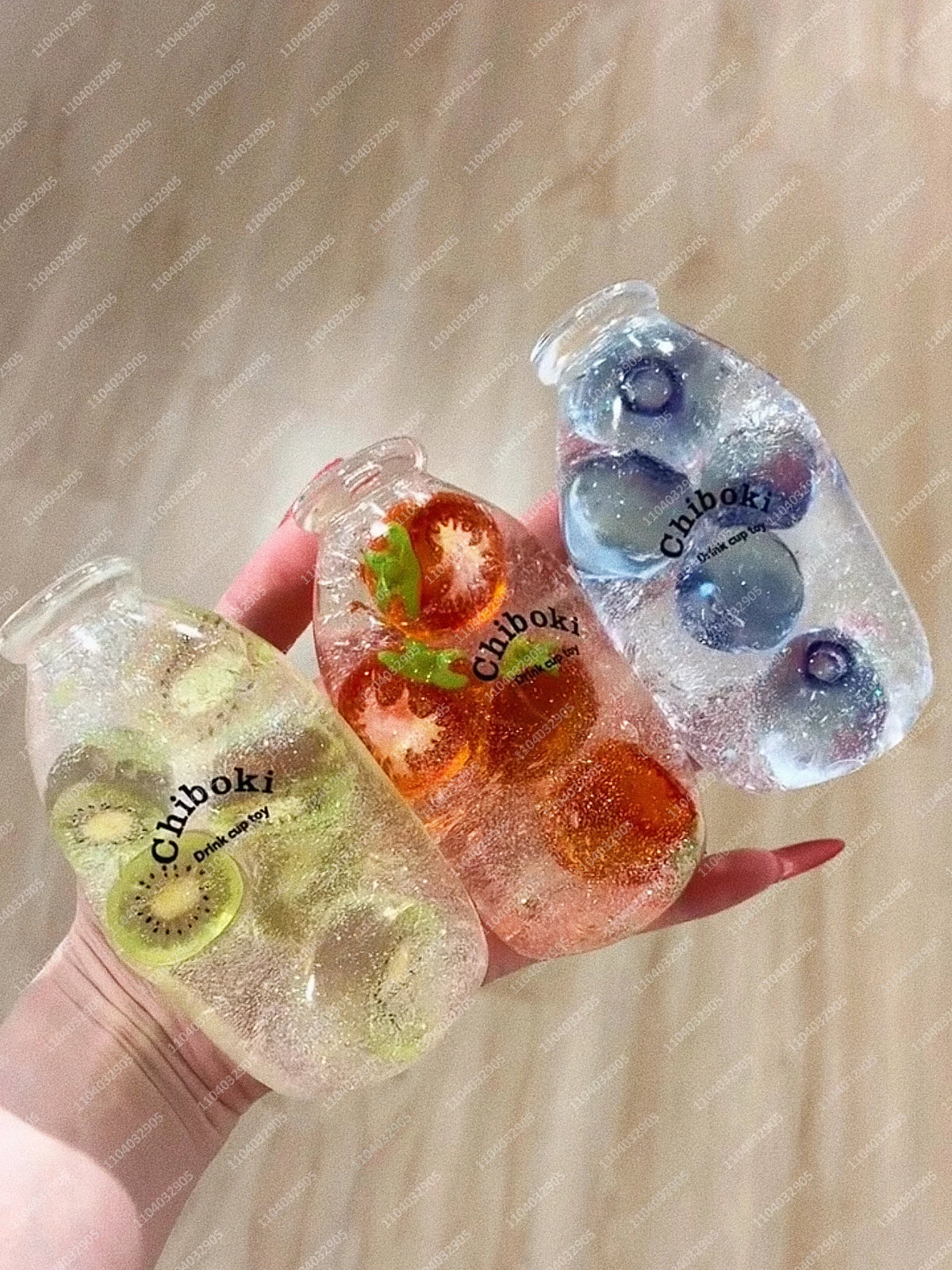 Three clear glass bottles filled with colored liquid and fruit pieces, held by a hand.