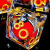A close-up of a resin die with a red core and gold spinning dragon eye, resting on a reflective black surface.