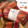 A ball of multi-colored gradient acrylic yarn in red, orange, and brown is shown on a knitted fabric background.