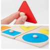A red triangular wooden shape sorter puzzle with a small white peg being inserted by a finger.