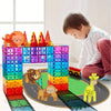 A boy is building a structure with colorful magnetic blocks featuring dinosaur and animal figures.