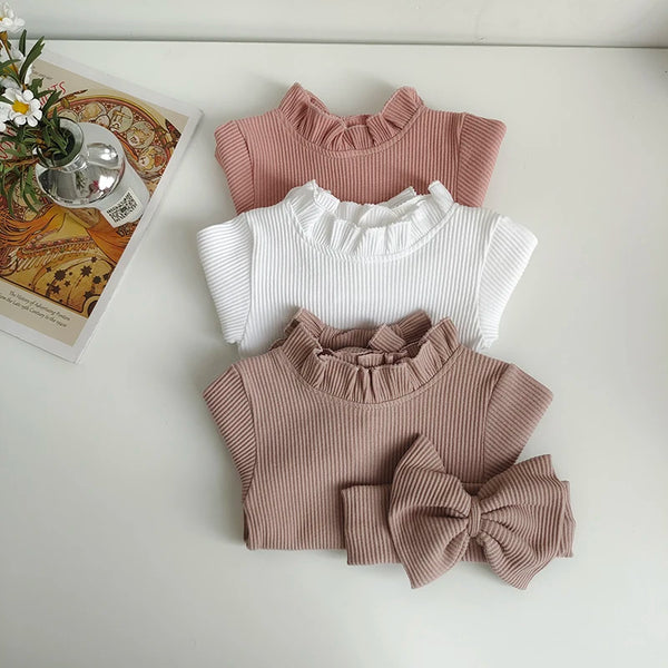 A set of three knitted tops for toddlers in pink and white, including a bow headband.