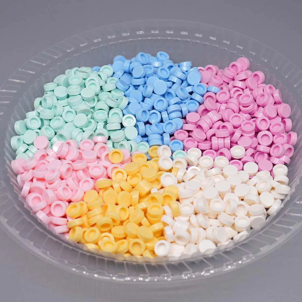 A clear plastic container filled with various colored plastic beads for DIY squishy toys and stress relief crafts