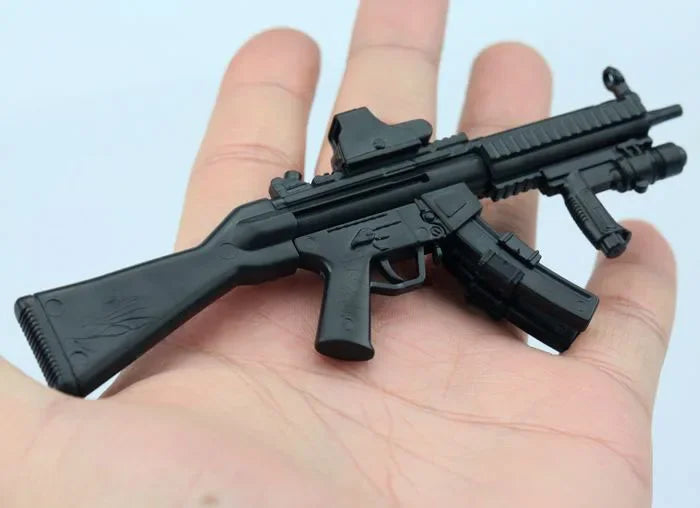 A black 1:6 scale MP5SD5 submachine gun model kit resting on a person's hand.